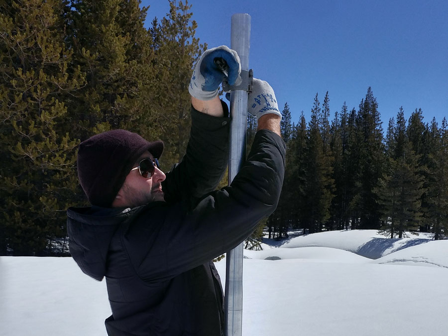 A man in the snow measures snow-water content.