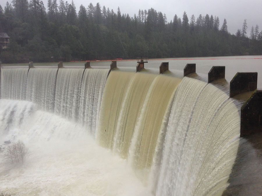 A curved dam with water rushing over. 