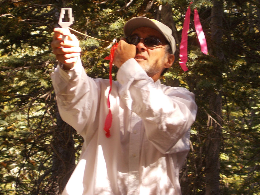 A man holds a measuring device that looks like a sling-shot.