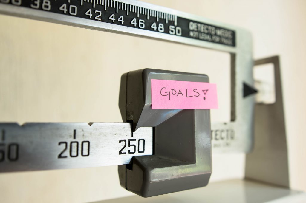 A physician beam scale has a post-it note labeled "goals" taped to it.