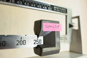 A physician beam scale has a post-it note labeled "goals" taped to it.