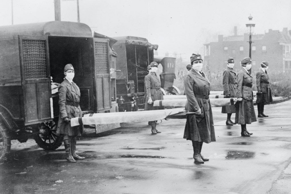 Red Cross workers wearing surgical masks carry beds out of trucks