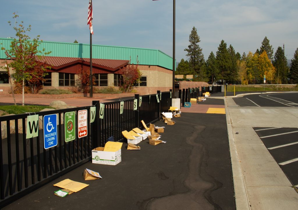 A fence in front of an elementary school has school supplies dropped off in front of it