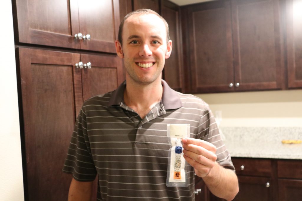 Scott King holding his DNA test in his hand while smiling