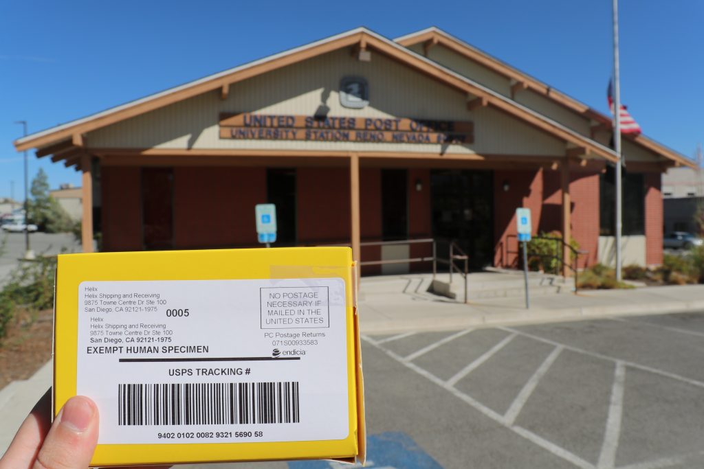 Scott holds his DNA test up in front of the post office, to show he is dropping it off at the post office