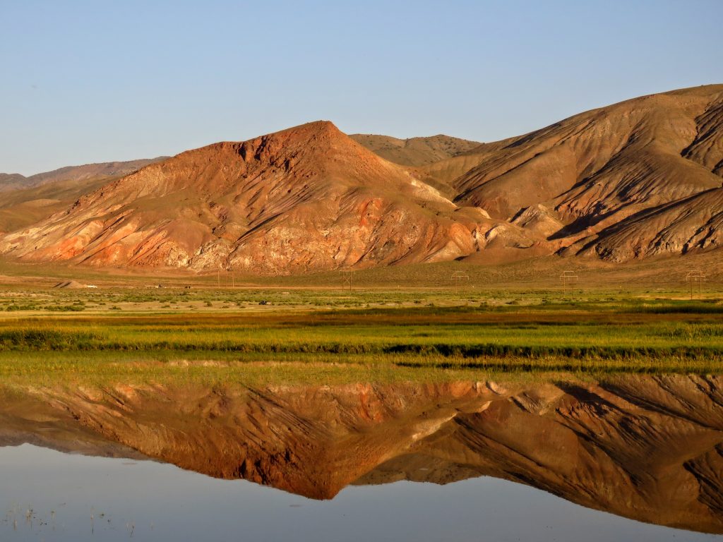 A landscape photo of the Dixie Valley. Mountains in the background are reflected on a body of water in the foreground.