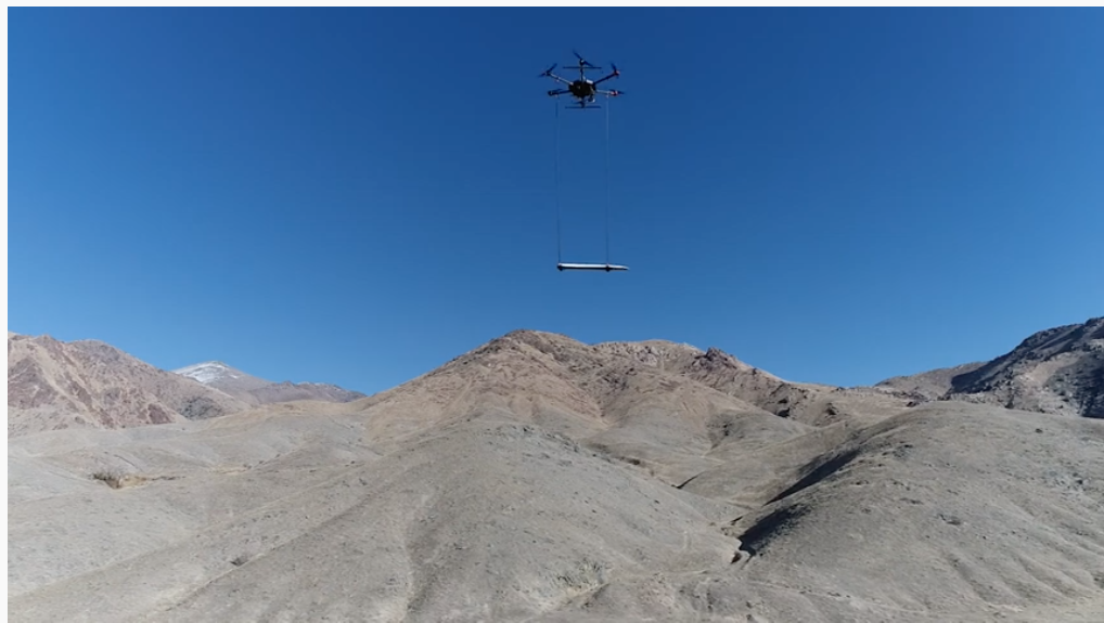 A large drone flies over Nevada mountains carrying magnetic sensing equipment that can identify geological areas that may contain geothermal systems.
