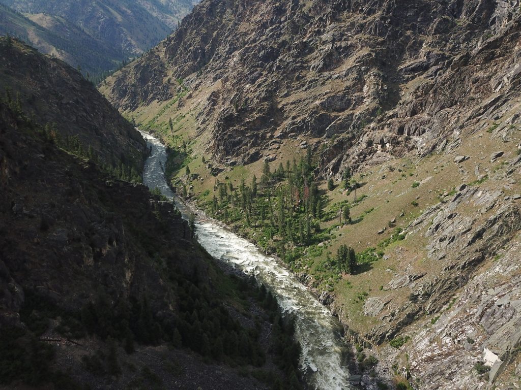 A river with lots of whitewater rapids carves its way through granite cliffs and mountains.