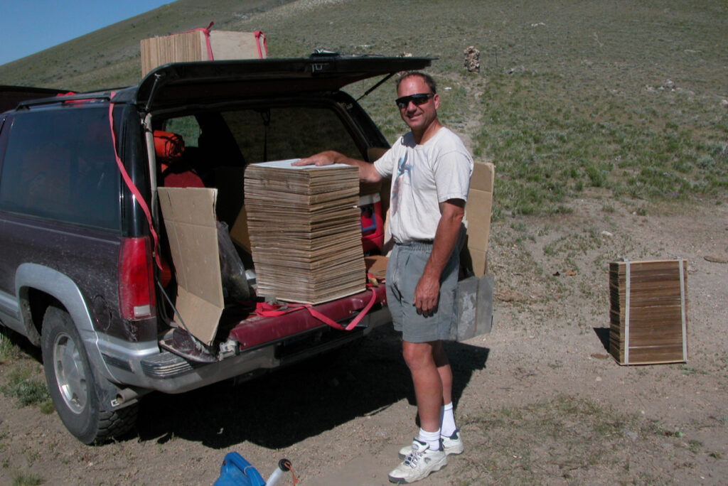 Jerry Tiehm stands next to large stack of cardboard plant presses on tailgate of vehicle