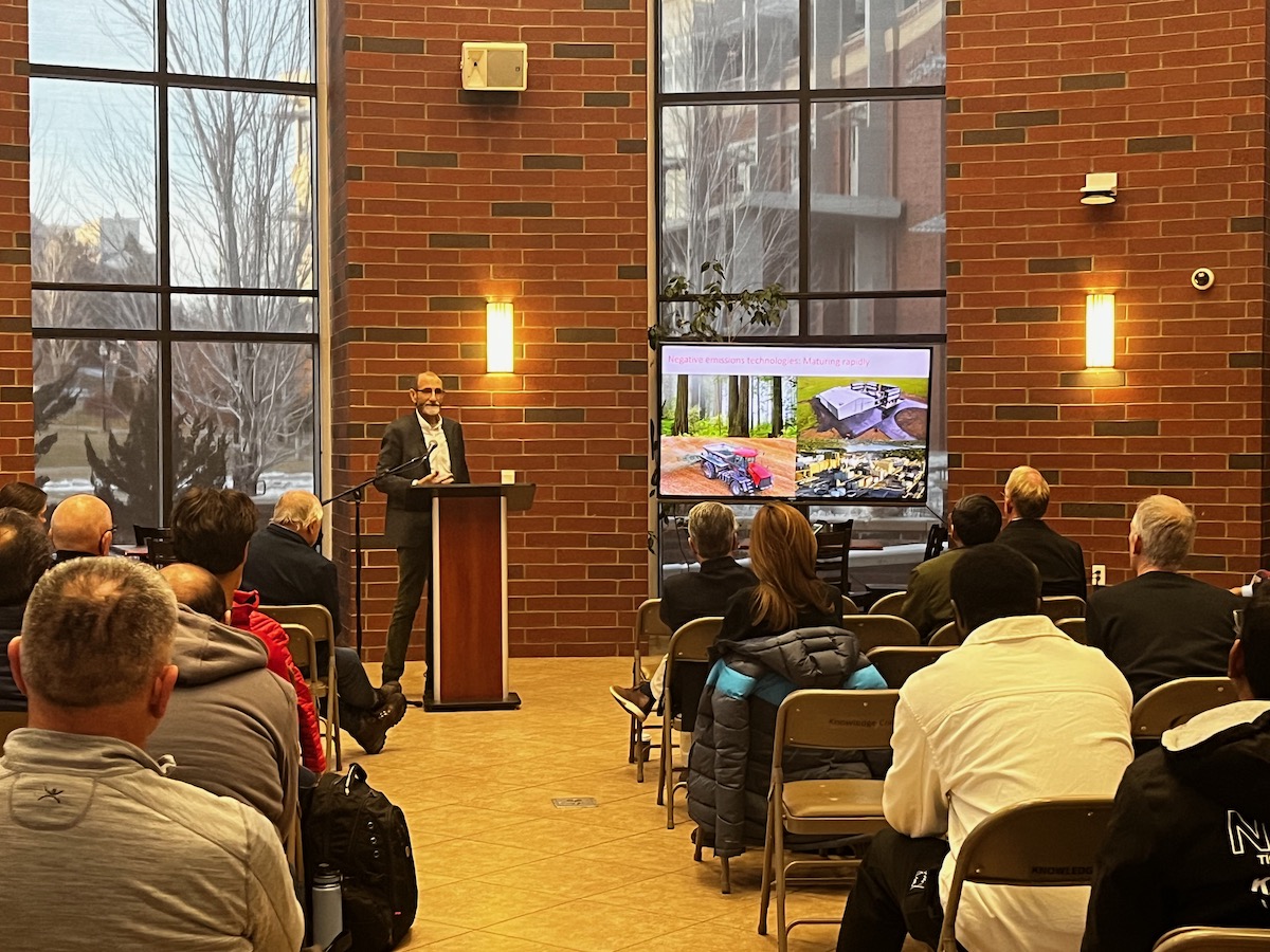 Chris Field stands at podium presenting to crowd of people during UNR Energy Solutions Forum