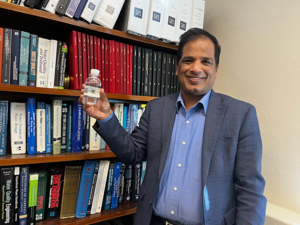 man holding bottle of water in front of bookshelf