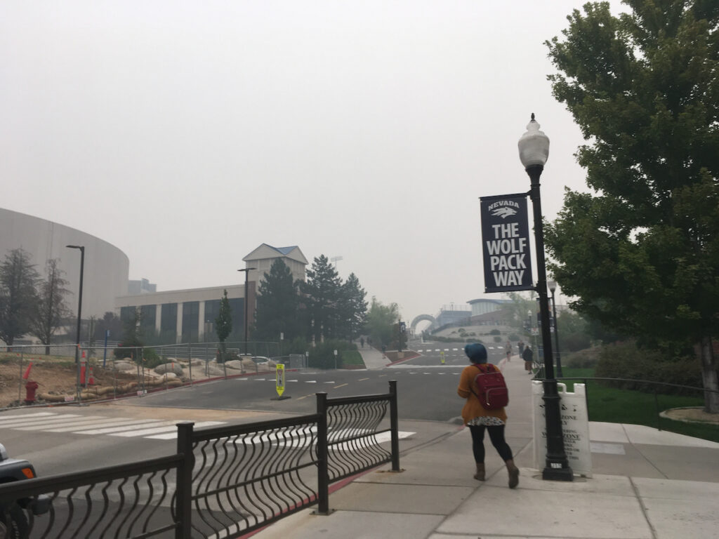 student walks on sidewalk at smoky UNR campus