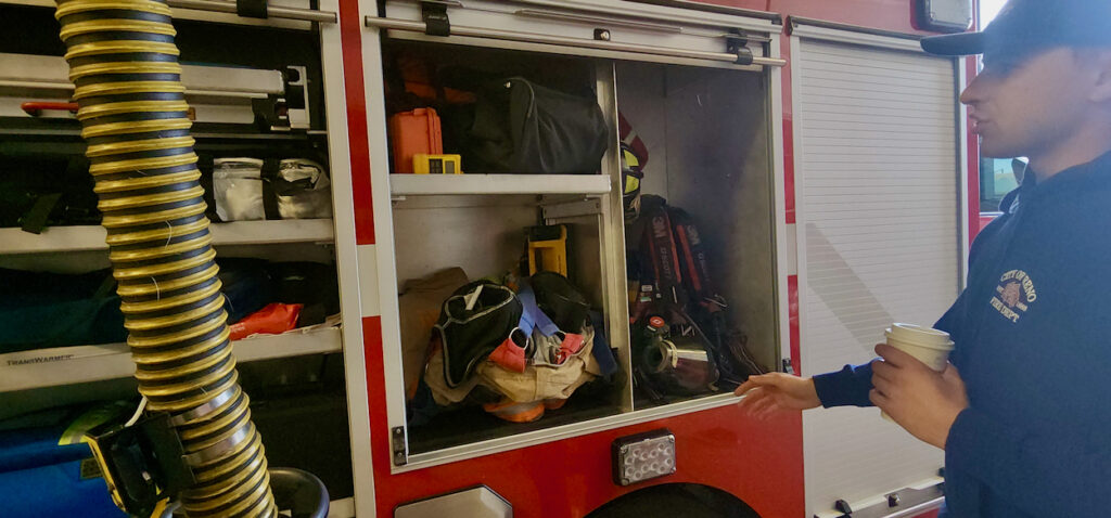 firefighter points to equipment in truck