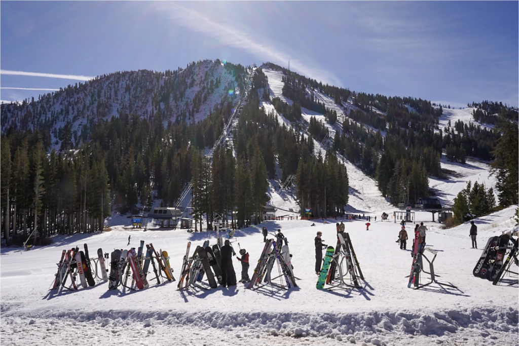 at mt. rose on a sunny day, skiiers and snowboarders at the base of the mountain prepare themselves to go up the ski lift.