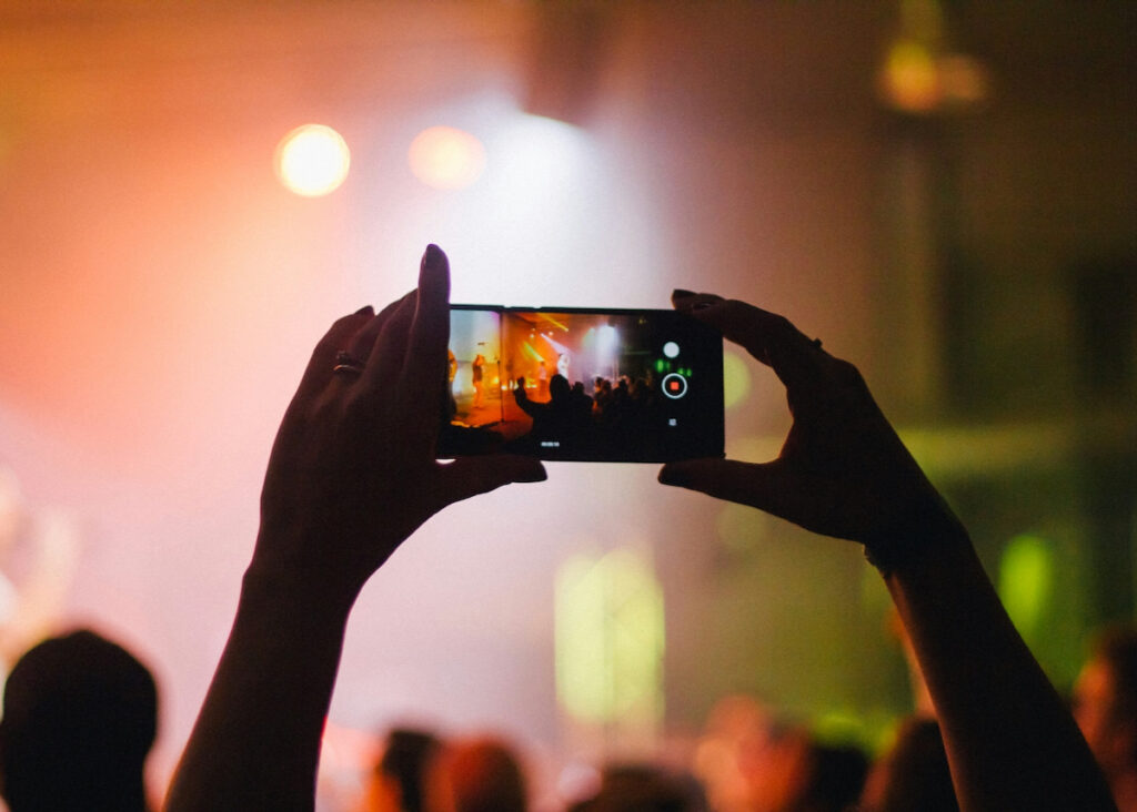 person holding phone above head while taking photo at concert