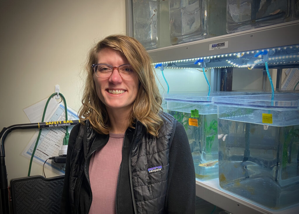 Biologist Misty Riddle stands in front of fish tanks.