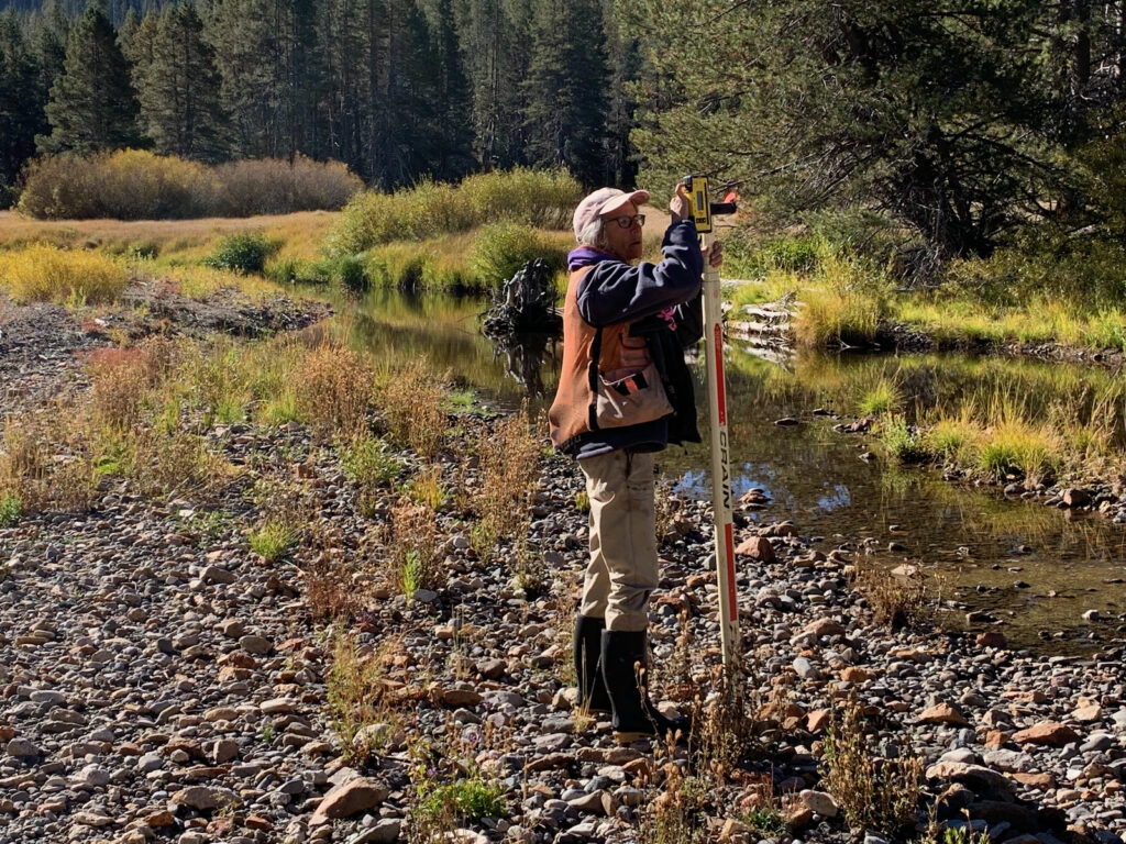 Person takes measurements near a creek