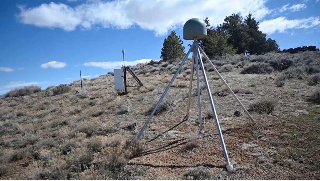 A GPS monument used to measure movement in Earth’s crust sits on top of metal tripod on dry Nevada hillside.