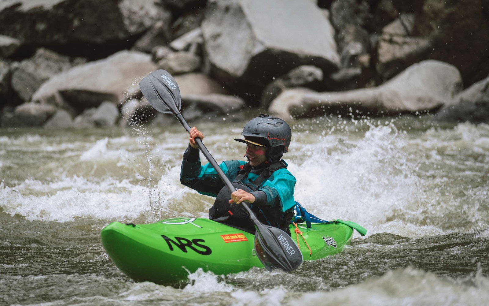 Brooke Hess paddles through whitewater in green kayak