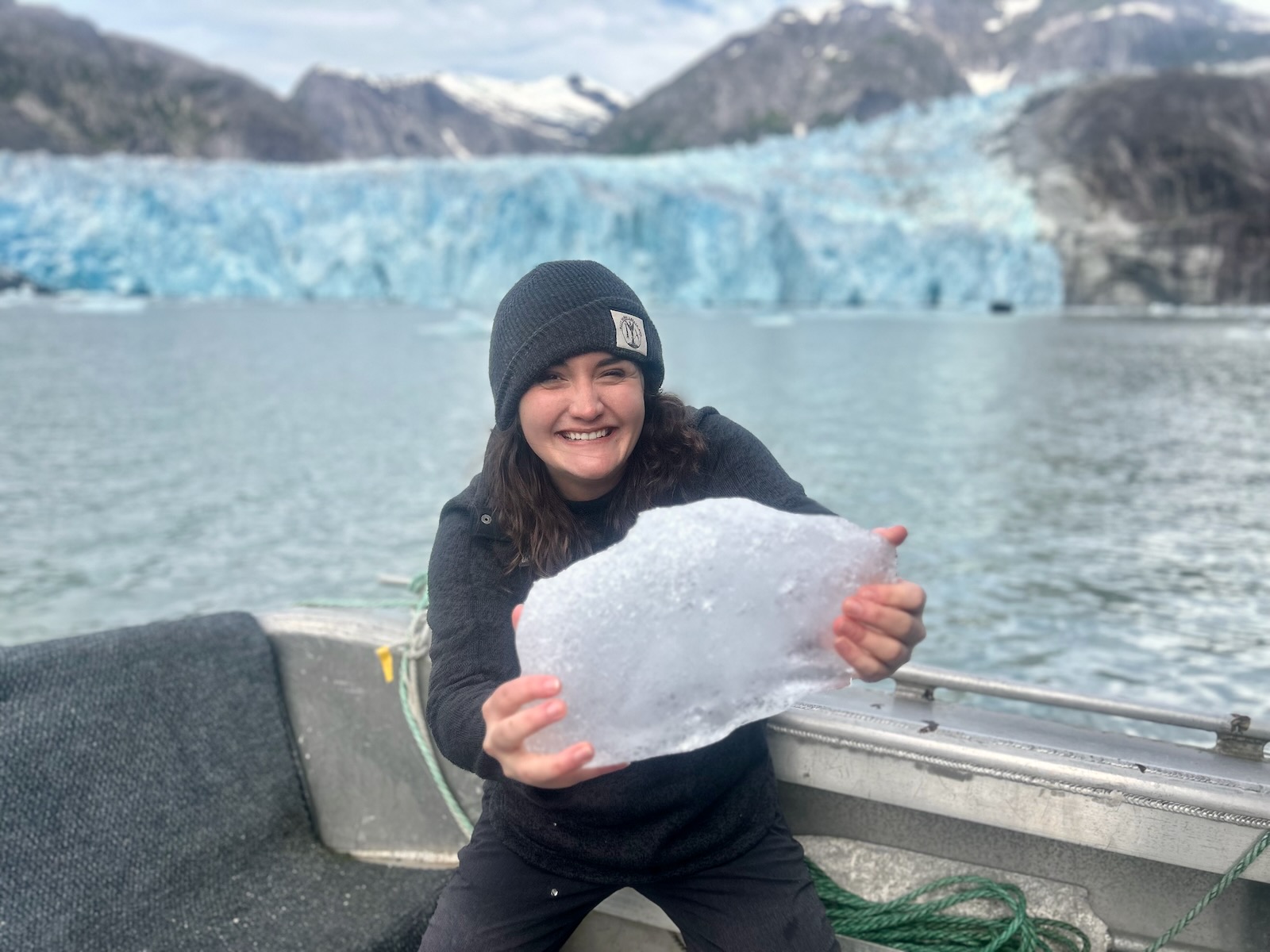 Shelby holding up a piece of ice in front of the LeConte Glacier in Southeast Alaska