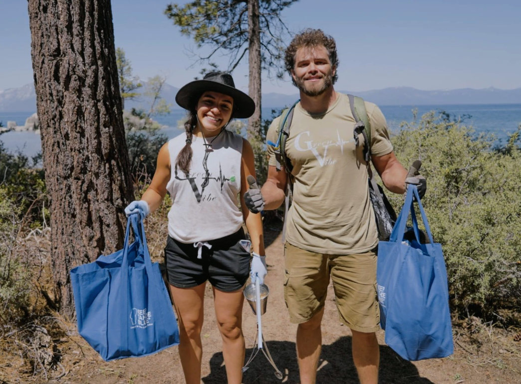 man and woman holding blue bags and removing trash near lake tahoe