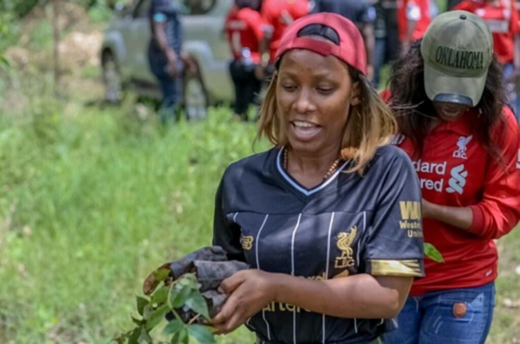 Two fans of the Liverpool Football Club in Uganda carrying trees to plant