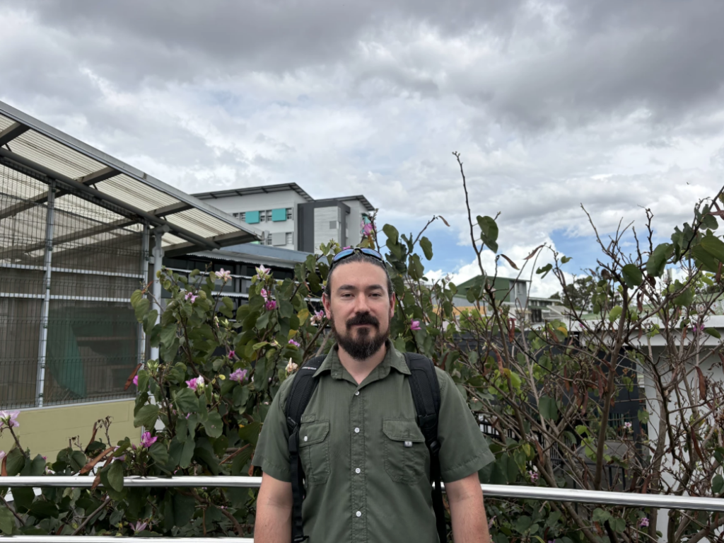 Emanuel Brenes stands near flowing bush in costa rica