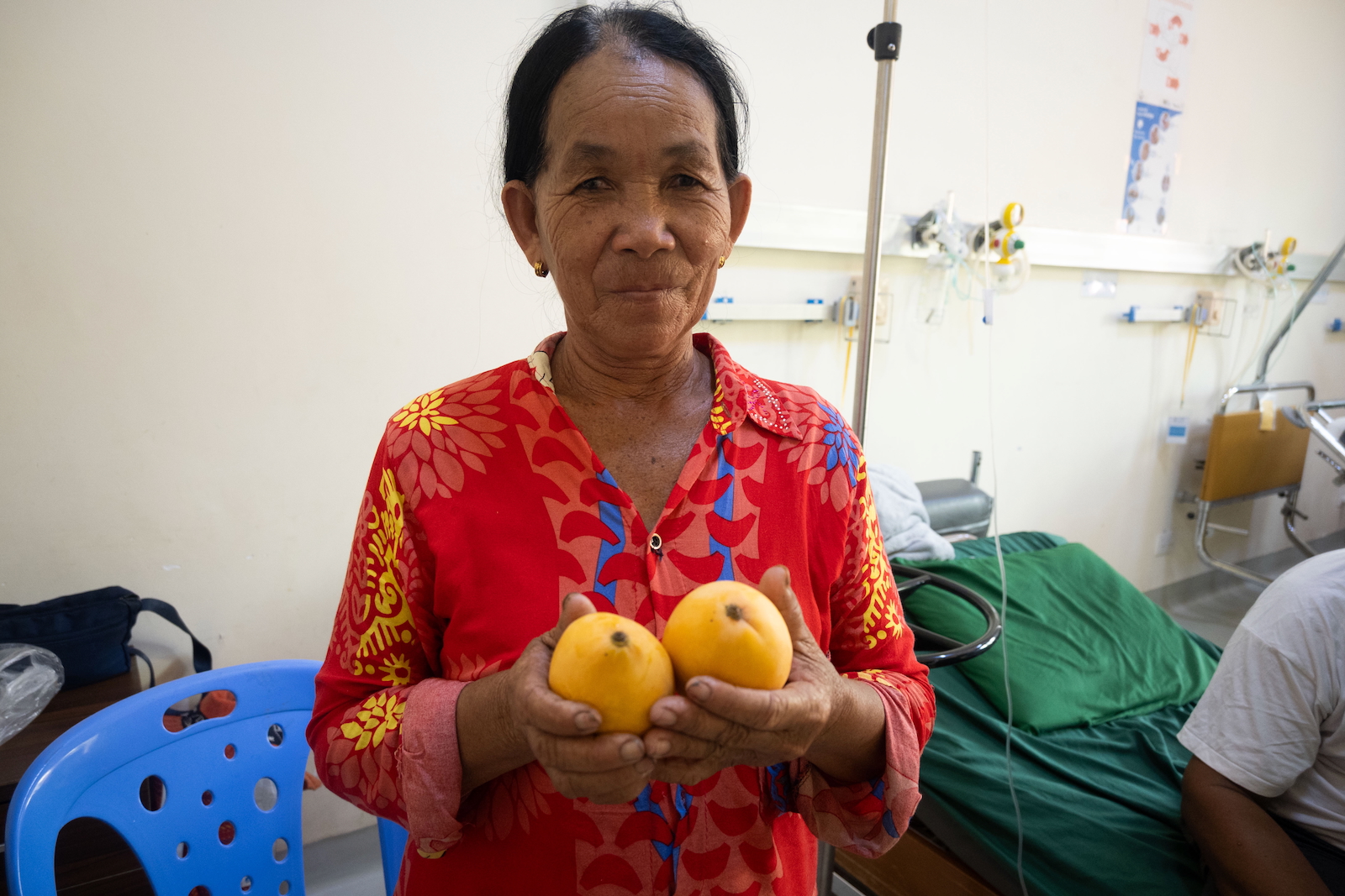 a woman holds out fresh mangoes that she brought for her husband.
