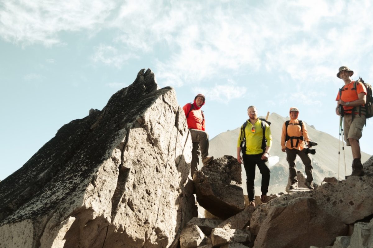 team of four geologists stands on rocky pass at Lassen Volcanic National Park